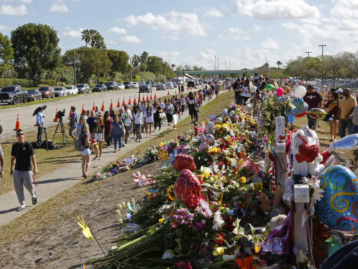 Parents and students walk by the memorial for the victims of the shooting at Marjory Stoneman Douglas High School on the way to open day: David Santiago/Miami Herald via AP