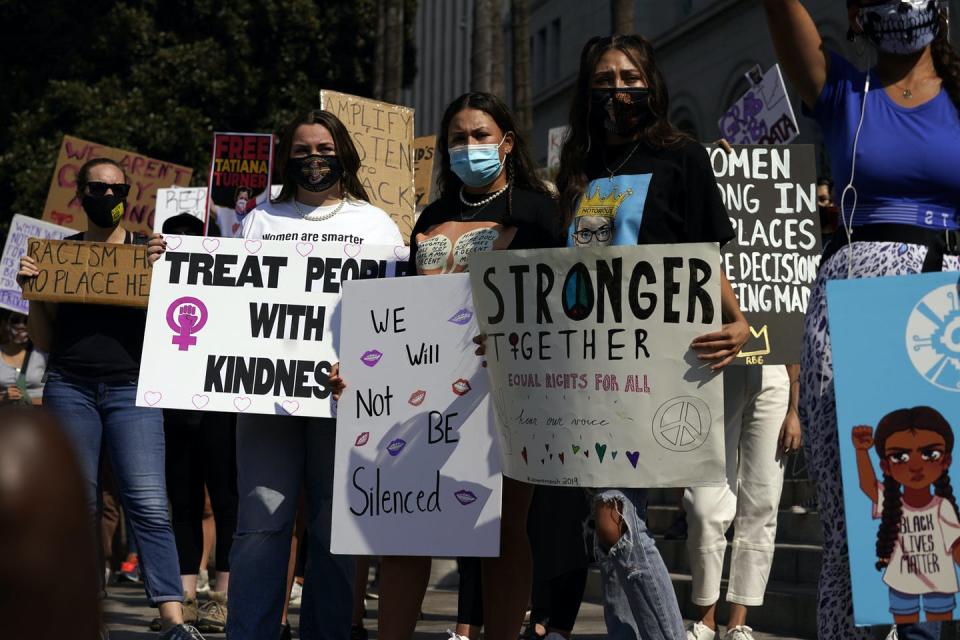 Demonstrators hold signs during a Women’s March.