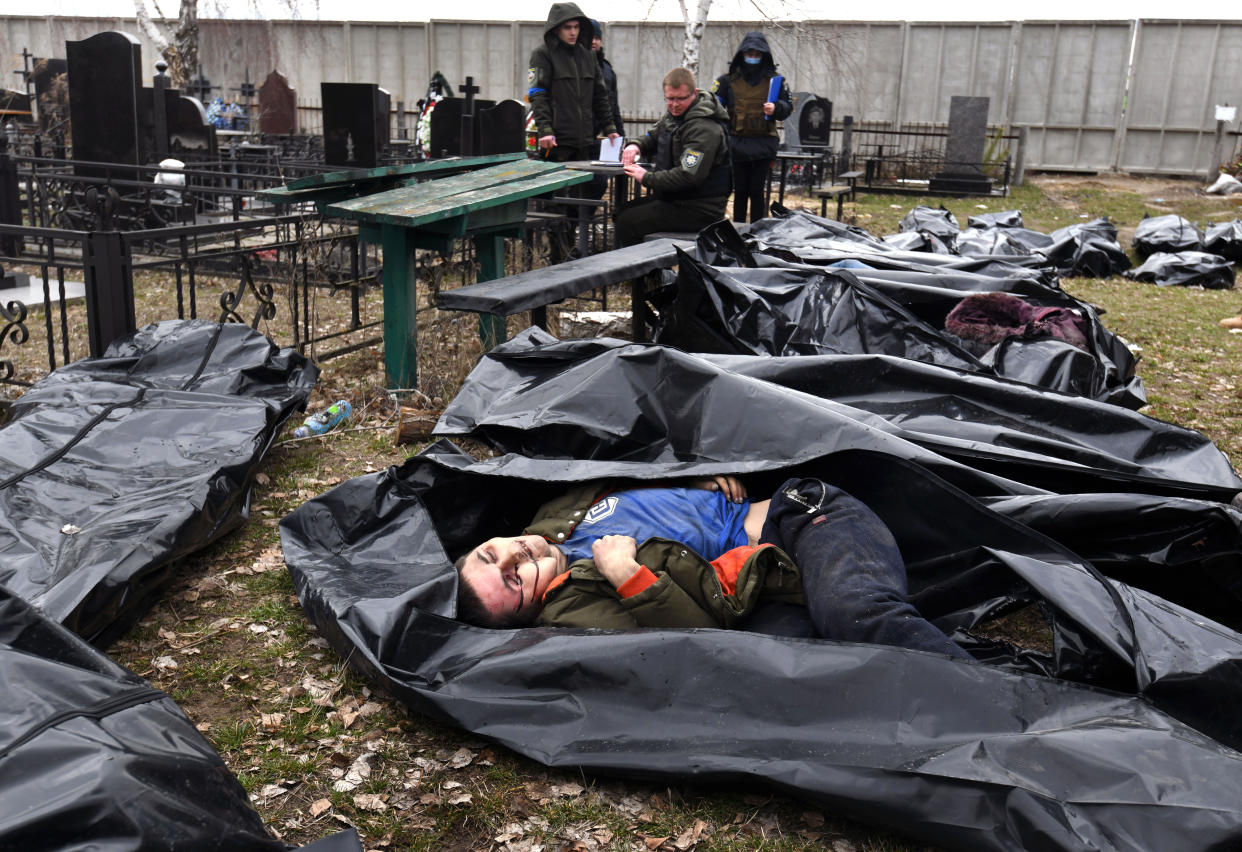 A clothed corpse lies exposed in a body bag in Bucha, Ukraine.