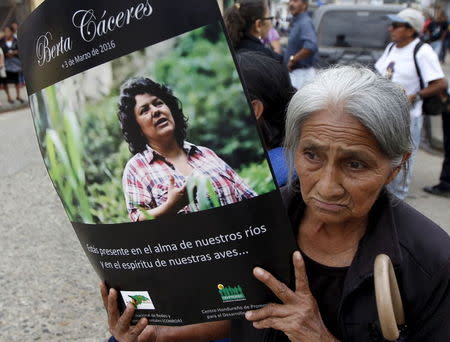 A woman holds up a poster with an image of slain environmental rights activist Berta Caceres along a street during her funeral in the town of La Esperanza, outside Tegucigalpa, Honduras March 5, 2016. REUTERS/Jorge Cabrera