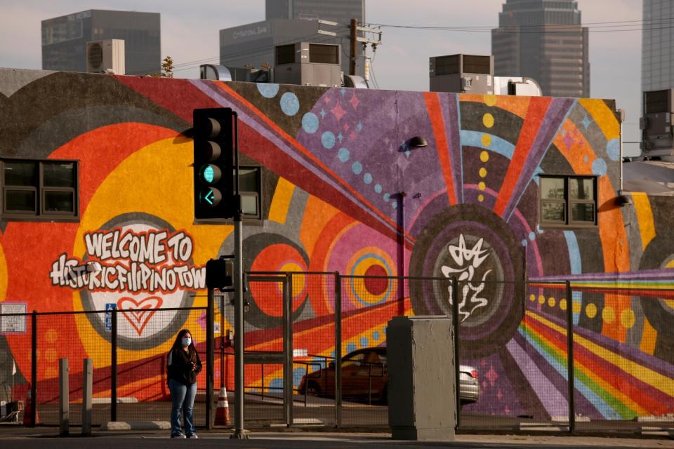 A woman stands in front of a mural.