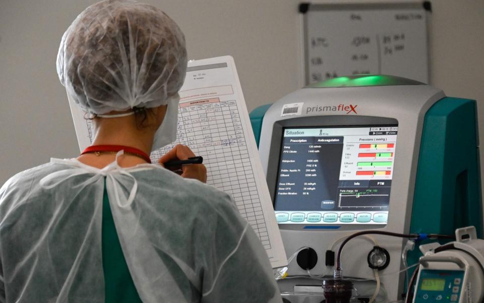 A nurse notes the medical data of a Covid-19 patient at the Pasteur hospital resuscitation unit in Colmar, eastern France - Sebastien Bozon/AFP