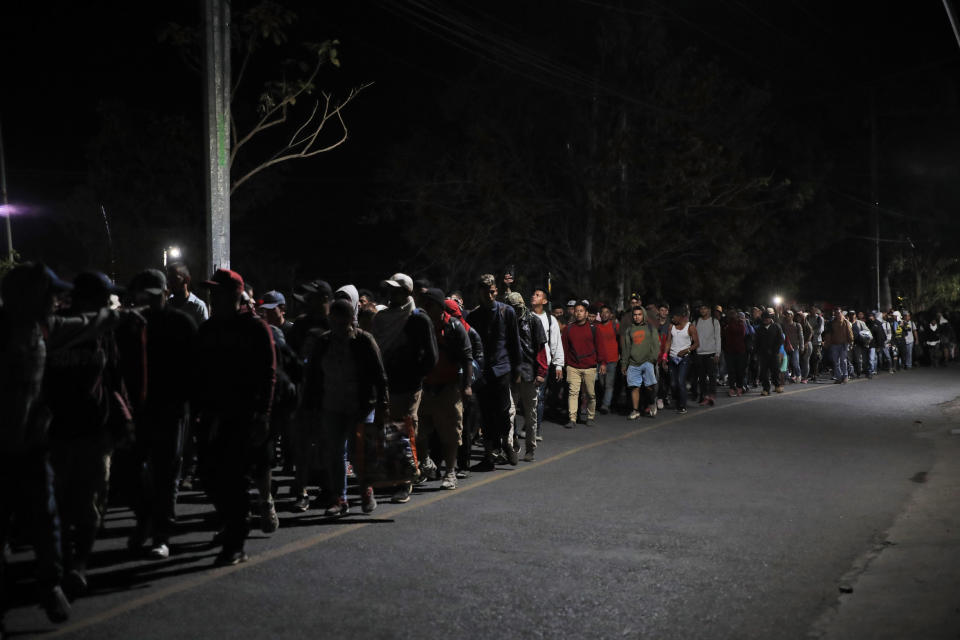 Central American migrants walk before sunrise toward the the Suchiate River as they leave Tecun Uman, Guatemala, and will cross the river into Mexico, Thursday, Jan. 23, 2020. Migrants hoping to reach the United States marooned in Guatemala waded en masse across the river leading to Mexico in an attempt to convince authorities there to allow them passage through the country. (AP Photo/Moises Castillo)