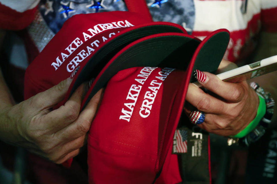FILE - In this June 2, 2016, file photo, a woman holds hats to get them autographed by Republican presidential candidate Donald Trump during a rally in San Jose, Calif. The notion of “blue states” and “red states” in the United States emerged during the aftermath of the contested 2000 election when TV networks used frequent on-air maps to show the breakdown between states going for Texas Gov. George W. Bush and Vice President Al Gore. Talk of red and blue states and even “Red America” and “Blue America” continues, and the relationship between the parties and their respective hues has grown even closer. (AP Photo/Jae C. Hong, File)