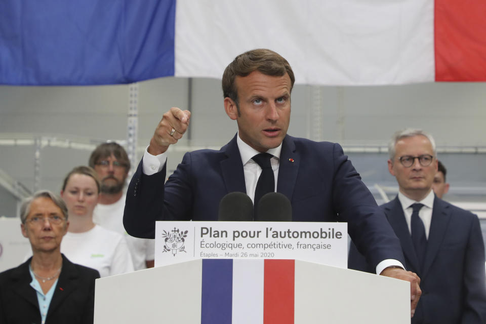 French President Emmanuel Macron delivers a speech flanked by French Economy and Finance Minister Bruno Le Maire, right, and French Minister for the Ecological and Inclusive Transition Elisabeth Borne, left, after a visit at the Valeo manufacturer plant, in Etaples, northern France, Tuesday May 26, 2020. France's government is injecting more than 8 billion euros ($8.8 billion) to save the country's car industry from huge losses wrought by virus lockdowns, and wants to use the crisis to make France the No. 1 producer of electric vehicles in Europe. (Ludovic Marin, Pool via AP)