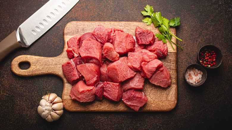 cutting board with raw beef chunks