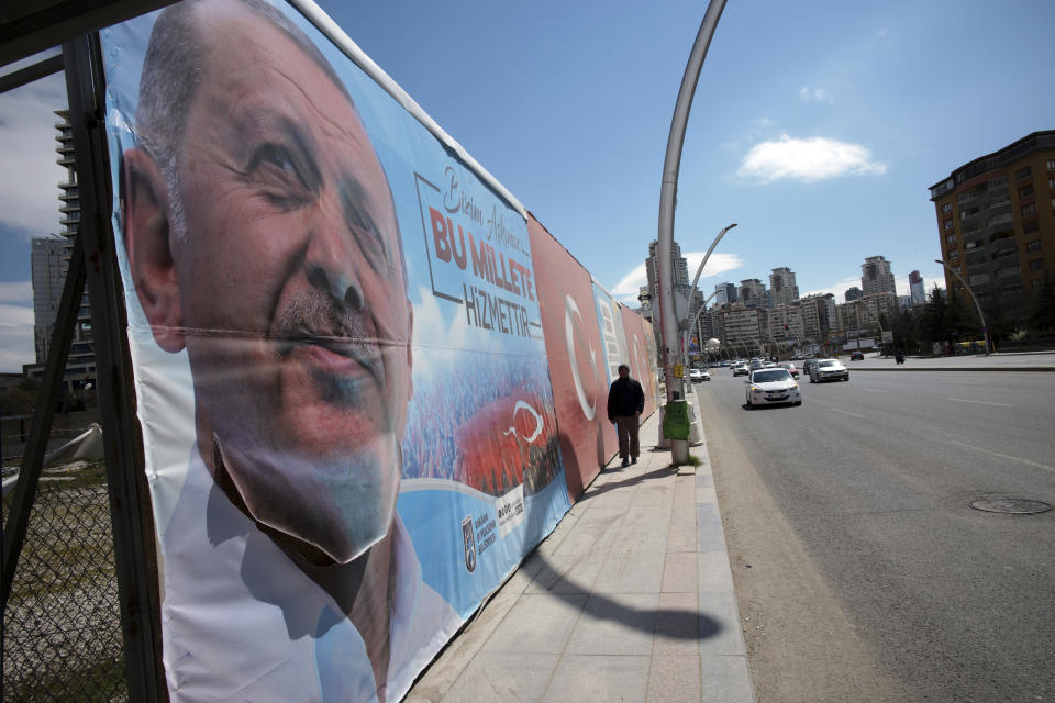 A man walks by huge posters of Turkey's President Recep Tayyip Erdogan, still displayed despite an election ban, near a polling station during the local elections in Ankara, Turkey, Sunday, March 31, 2019. Turkish citizens have begun casting votes in municipal elections for mayors, local assembly representatives and neighborhood or village administrators that are seen as a barometer of Erdogan's popularity amid a sharp economic downturn. (AP Photo/Burhan Ozbilici)