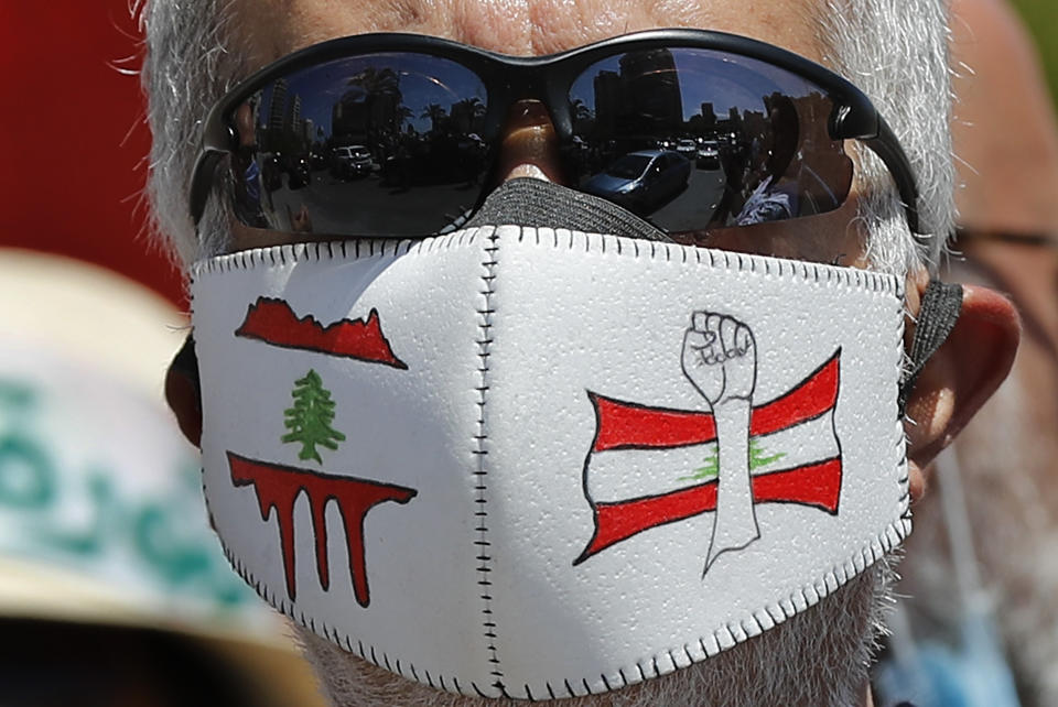 An anti-government protester wears a mask with Lebanese revolution logos to help curb the spread of the coronavirus, during a protest against a general amnesty law being proposed in Parliament, in Beirut, Lebanon, Thursday, May 28, 2020. (AP Photo/Hussein Malla)