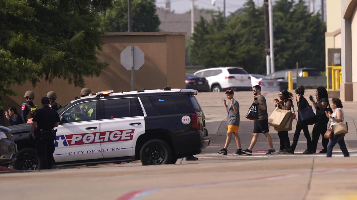 People raise their hands as they leave a shopping center following reports of a shooting, Saturday, May 6, 2023, in Allen, Texas. (AP Photo/LM Otero)