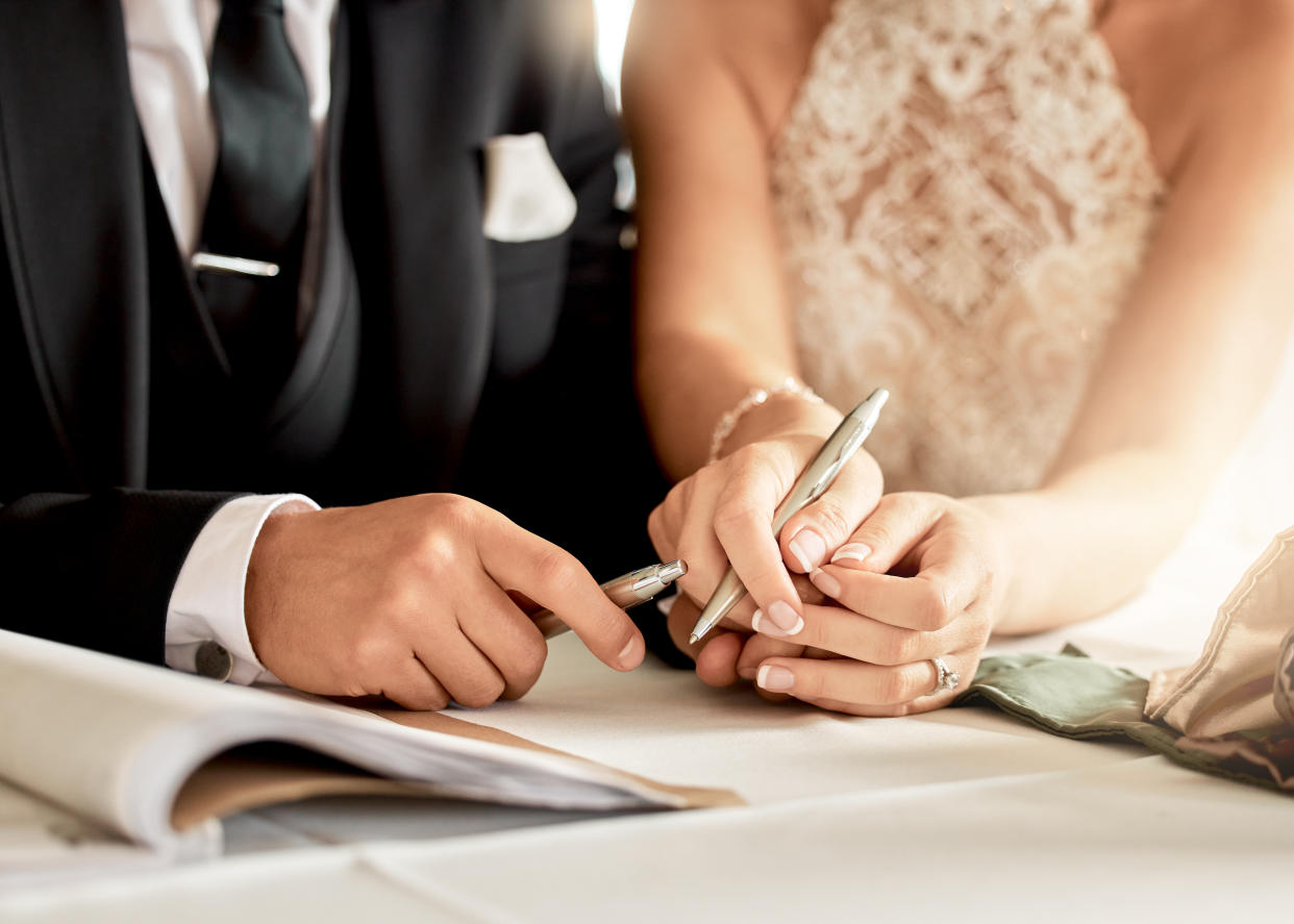 Couple sign wedding certificate, marriage registration and document paper for legal union. Closeup bride, groom and hands writing contract for celebration of love, commitment and agreement together