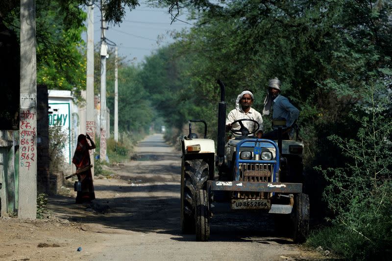 FILE PHOTO: A farmer drives his tractor along a village road in Mathura