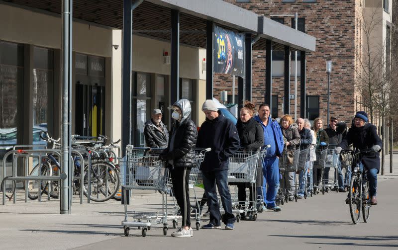 FILE PHOTO: People wait in a queue to enter a supermarket in Schulzendorf near Berlin, during the coronavirus disease (COVID-19) outbreak