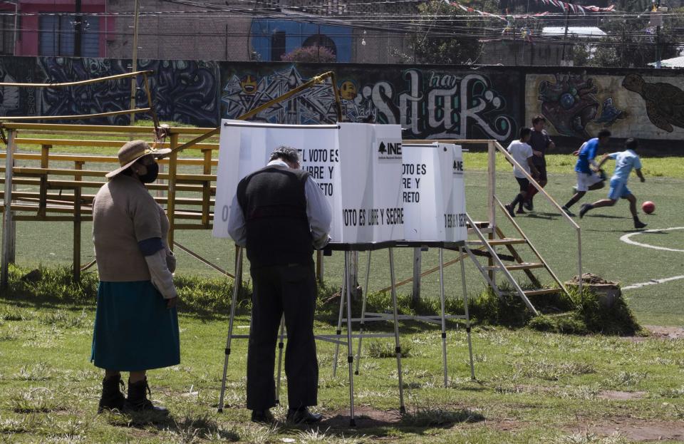 A couple votes in a non-binding referendum on whether Mexican ex-presidents should be tried for any illegal acts during their time in office, in San Miguel Topilejo, Mexico City, Sunday, August 1, 2021. (AP Photo/Christian Palma)