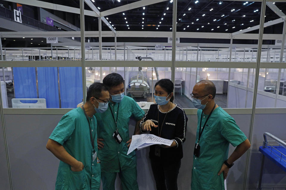 Medical workers make preparations at a temporary field hospital set up at Asia World Expo in Hong Kong, Saturday, Aug. 1, 2020. The new COVID-19 patient holding facility can accommodate up to 500 adult patients in stable conditions. The facility which is located near the Hong Kong International Airport is a big convention and exhibition facility and was previously used as a coronavirus testing center for incoming travelers. It's transformed into a treatment facility so that it helps freeing up hospital beds for the serious patients. (AP Photo/Kin Cheung)