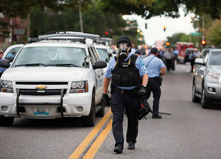 Police wear gas masks as they attempt to disperse a crowd that gathered after a shooting incident in St. Louis, Missouri August 19, 2015. REUTERS/Kenny Bahr