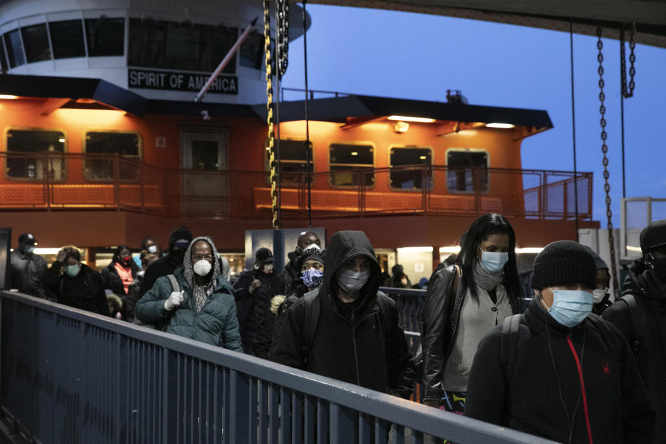 FILE- In this April 21 2020 file photo, passengers wear face masks to help curb the spread of coronavirus, leave the Staten Island Ferry in New York. An Associated Press study of COVID-19 cases by zip code in New York City has found more cases per capita in Staten Island, the least congested of the five boroughs than in some of the more densely populated areas of Manhattan, Brooklyn and Queens. (AP Photo/Mark Lennihan, File)