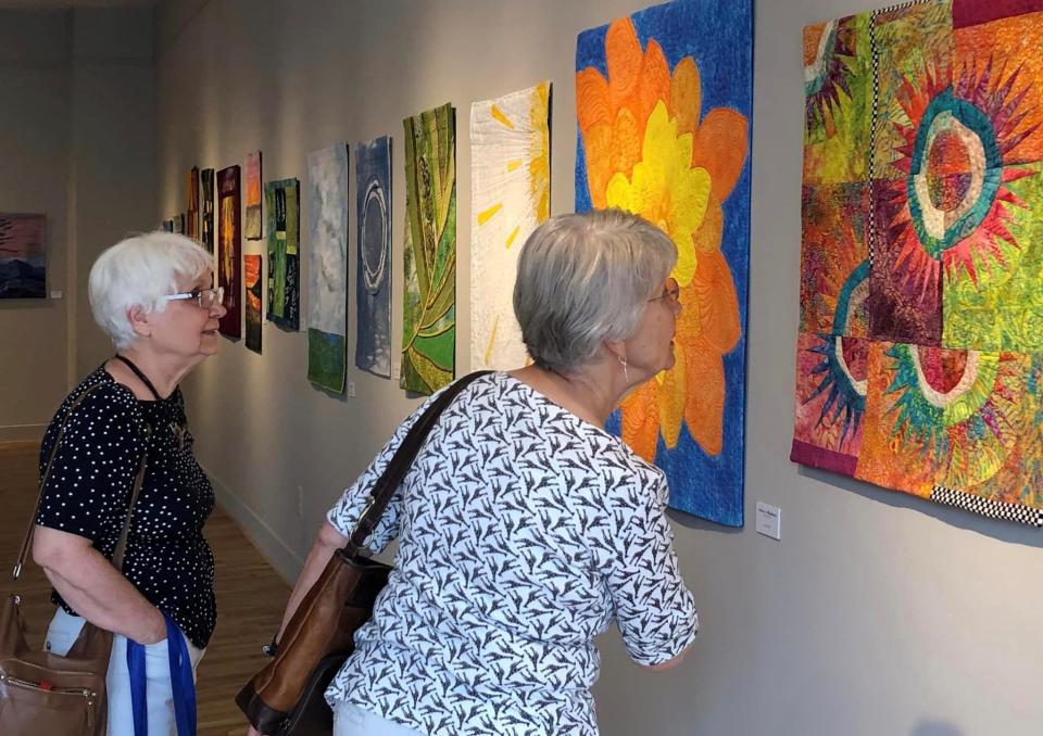 Friends from left to right, Therese Quidato and quilter Inge Killingsworth both of Sutherland admire the "Northern Lights" quilt made by Karen Stockwell of Maggie Valley, N.C. during Petersburg Area Art League's exhibition of art quilts on July 15, 2023.