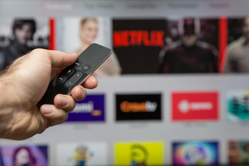 Montreal, Сanada - January 3, 2016: Human hand holding The 4th generation Apple TV new Siri remote browsing the channel selections. The Apple TV is produced by Apple Inc.