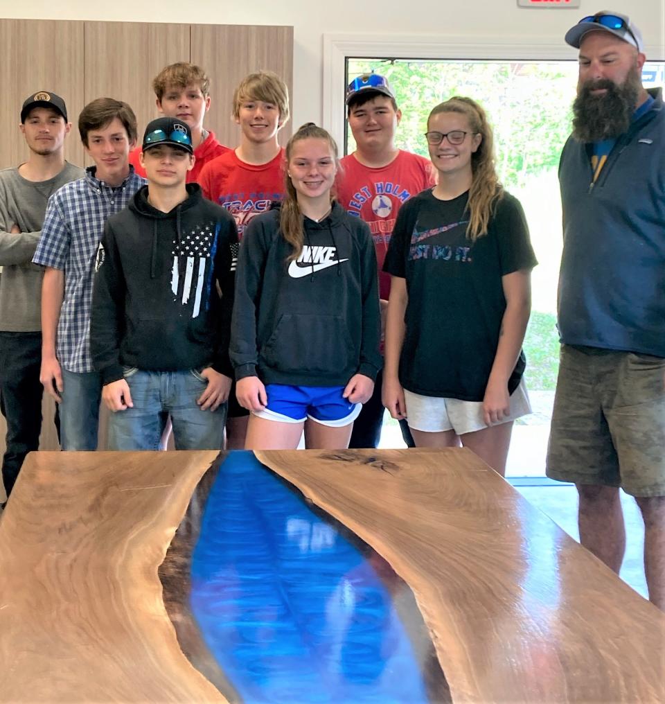 West Holmes Building & Trades instructor Dave McMillen (at right) and his sophomore students in the B&T program deliver the second custom made art table to the Holmes Center for the Arts.