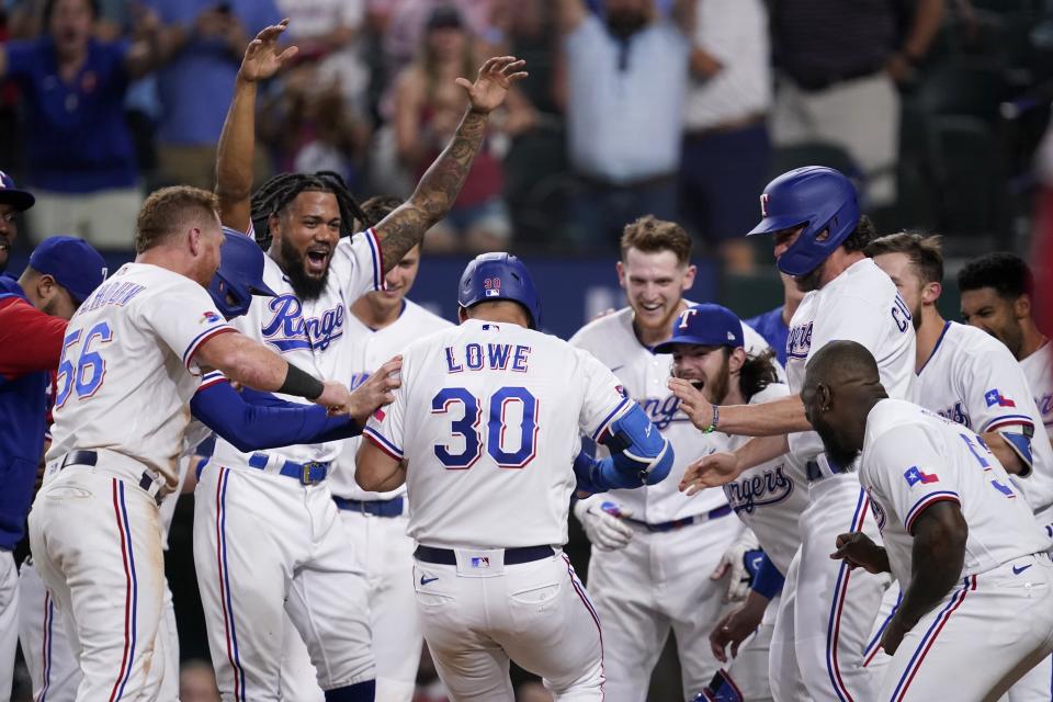 The Texas Rangers celebrate a walk-off, two-run home run hit by Nathaniel Lowe (30) during the 10th inning of the team's baseball game against the Los Angeles Angels, Wednesday, May 18, 2022, in Arlington, Texas. (AP Photo/Tony Gutierrez)