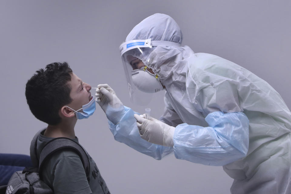 A healthcare worker takes a swab sample from a passenger who arrived at the Rafik Hariri International Airport in Beirut, Lebanon, Wednesday, July 1, 2020. Beirut's airport is partially reopening after a three-month shutdown and Lebanon's cash-strapped government is hoping that thousands of Lebanese expatriates will return for the summer, injecting dollars into the country's sinking economy. (AP Photo/Bilal Hussein)