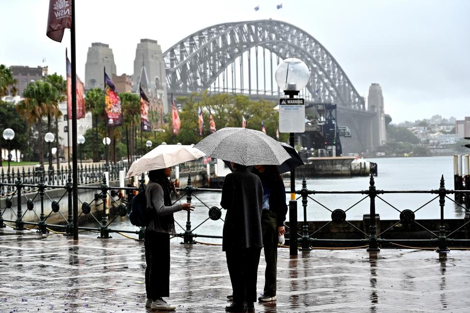 Visitors talk before the Harbour Bridge on the Circular Quay in Sydney on October 26, 2020. - Australia has been relatively successful in containing the spread of the coronavirus, with about 27,500 cases and 905 deaths in a population of 25 million. (Photo by Saeed KHAN / AFP) (Photo by SAEED KHAN/AFP via Getty Images)