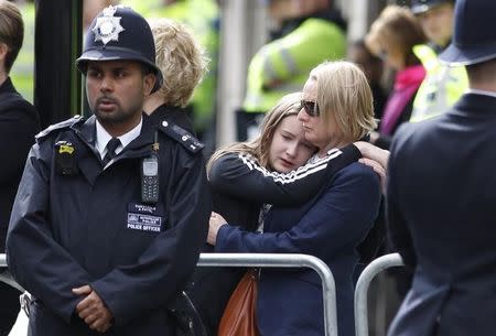 An onlooker reacts as the coffin of PC Keith Palmer, who was killed in the recent Westminster attack, is transported from the Palace of Westminster, where it laid overnight, to his funeral at Southwark Cathedral in central London, Britain April 10, 2017. REUTERS/Peter Nicholls