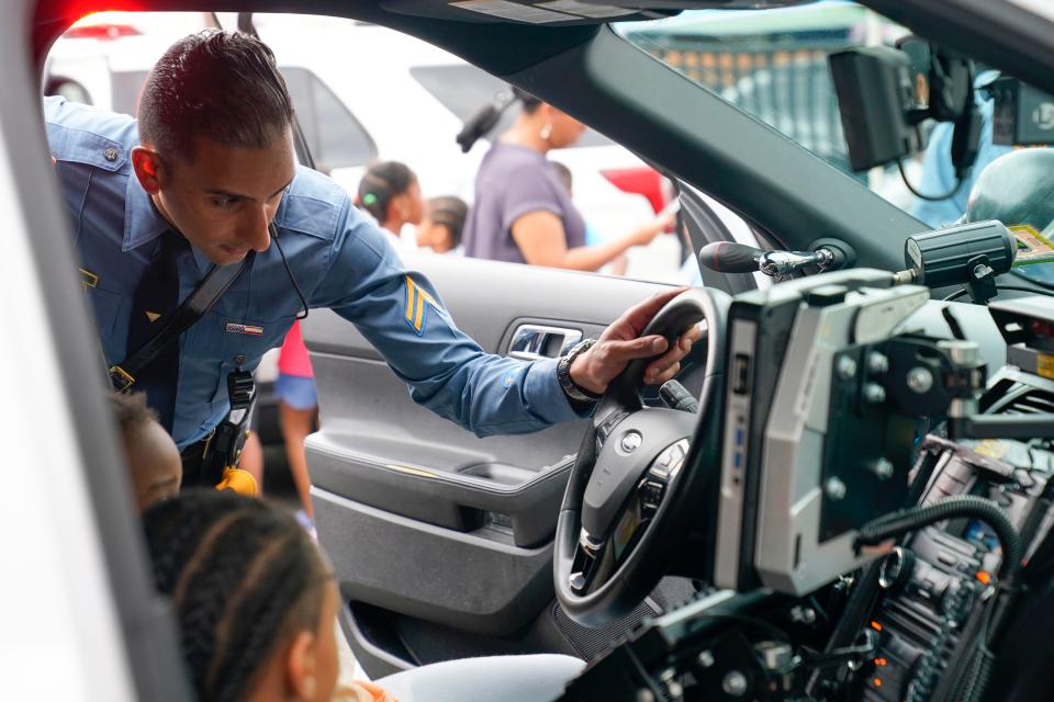 New Jersey State Police Trooper Mudduser Malik shows campers the inside of a police car at the Boys & Girls Club of Paterson on Tuesday, Aug. 8, 2023.