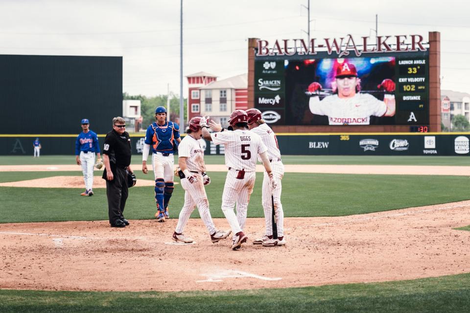 Arkansas baseball's Peyton Holt (left) celebrates with teammates after hitting a go-ahead two-run homer against Florida, April 27, 2024.