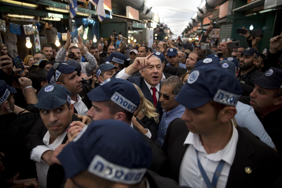 FILE - In this April 2, 2019 file photo, Israeli Prime Minister Benjamin Netanyahu, head of the Likud party, center, is escorted by security guards during a visit to the Ha'tikva market in Tel Aviv, Israel. As Netanyahu becomes Israel’s longest-serving prime minister, he is solidifying his place as the country’s greatest political survivor and the most dominant force in Israeli politics in his generation. (AP Photo/Oded Balilty, File)