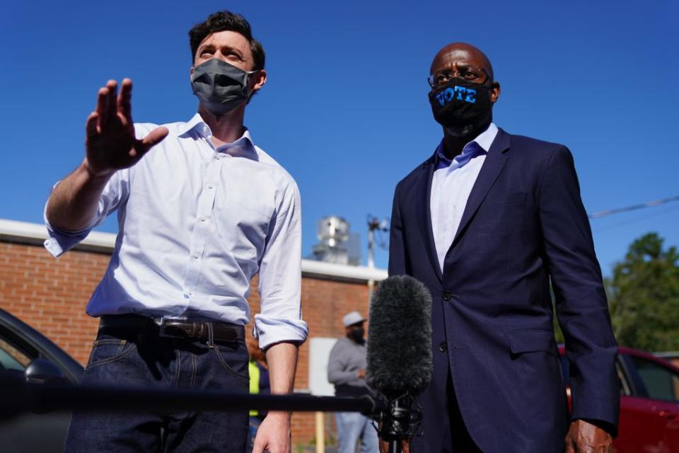 Democratic U.S. Senate candidates Jon Ossoff and Rev. Raphael Warnock hand out lawn signs at a campaign event on October 3, 2020 in Lithonia, Georgia. (Photo by Elijah Nouvelage/Getty Images)