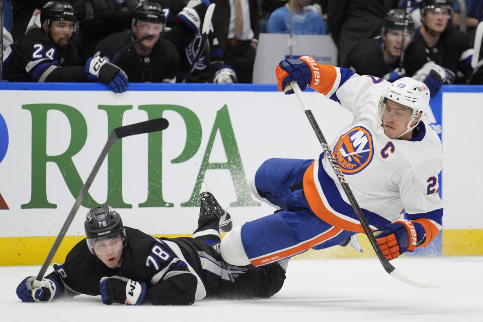 Tampa Bay Lightning defenseman Emil Martinsen Lilleberg (78) and New York Islanders left wing Anders Lee (27) go down after clearing the puck during the first period of an NHL hockey game Saturday, March 30, 2024, in Tampa, Fla. (AP Photo/Chris O'Meara)