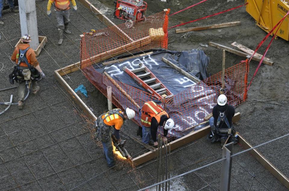 Workers build forms Wednesday, Feb. 12, 2014, around the area at a construction site in Seattle where what is believed to be an ice age mammoth tusk was discovered on Tuesday. Work pouring cement at the site was continuing, but workers blocked off the area where the tusk was found. Paleontologists from the University of Washington hope to move the tusk to a museum on campus. (AP Photo/Ted S. Warren)