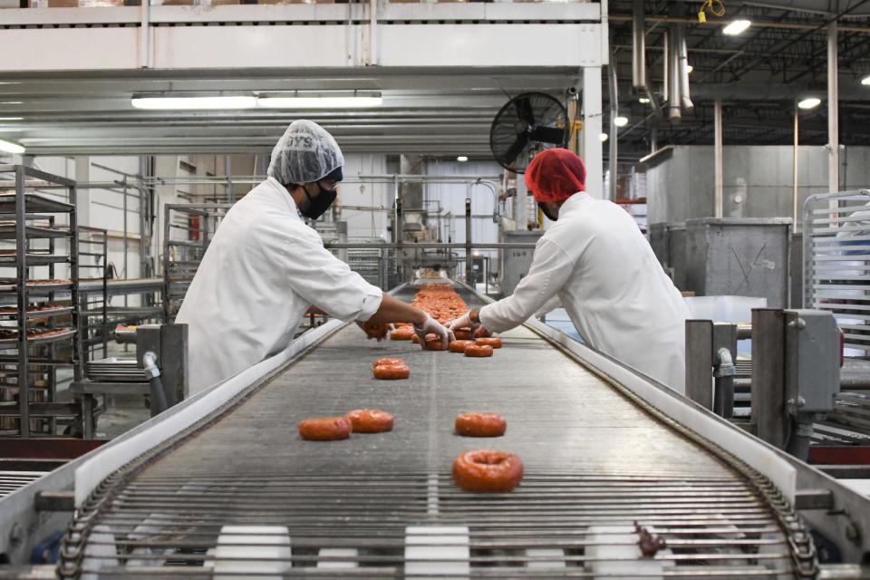 Jaime Salinas, left, and Matt Cooley cull freshly-baked donuts from the line at the Quality Dairy Bakery Plant in REO Town, Monday, Feb. 1, 2021, in Lansing.