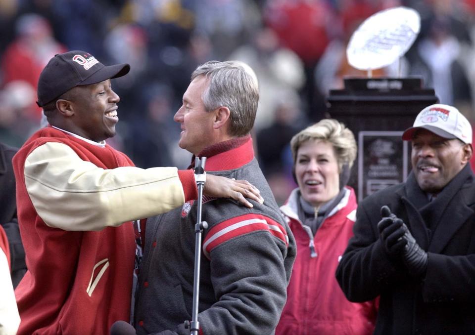 Mike Doss hugs head coach Jim Tressel at Ohio Stadium during their national championship celebration. At right is Tressel's wife and former Ohio State two time Heisman Trophy winner Archie Griffin. The national championship trophy is in the background.