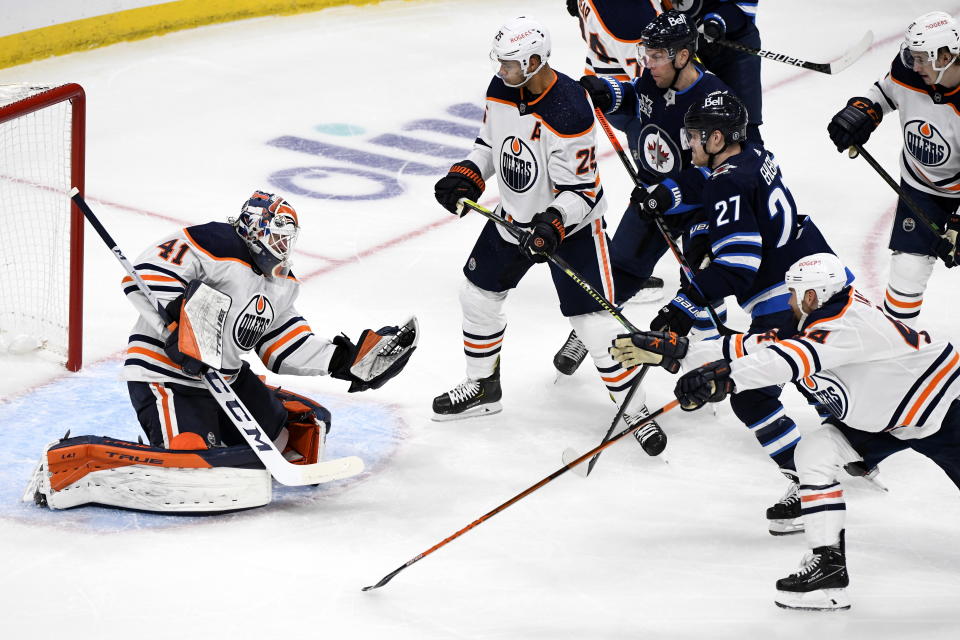 Edmonton Oilers goaltender Mike Smith (41) makes a save on a Winnipeg Jets shot as players look for the rebound during the first period of an NHL game against the Winnipeg Jets, in Winnipeg, Manitoba on Sunday, May 23, 2021. (Fred Greenslade/The Canadian Press via AP)