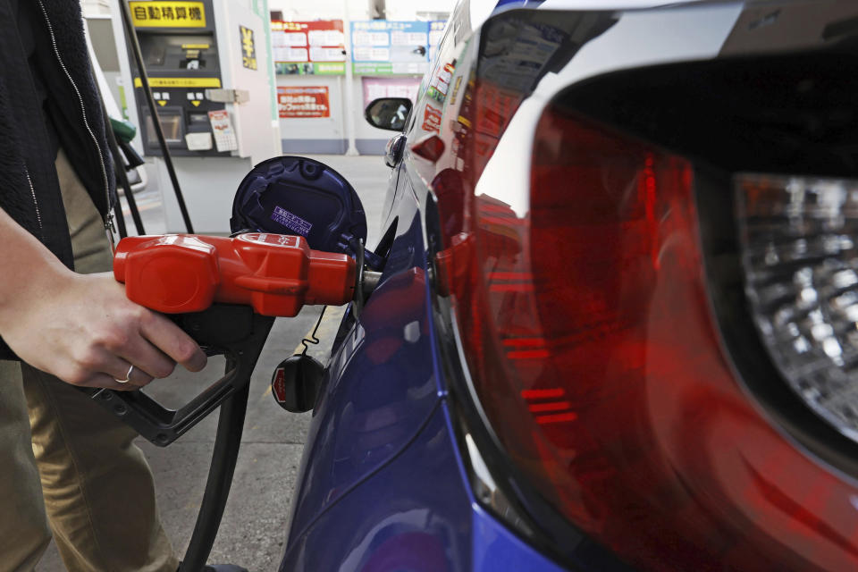 A person fills petrol at a fuel station in Tokyo on March 16, 2022. Japan racked up a trade deficit in April, marking the 21st month in a row of deficits, although it declined dramatically compared to a year ago, as exports recovered, according to government data released Thursday, May 18, 2023. (Kyodo News via AP)