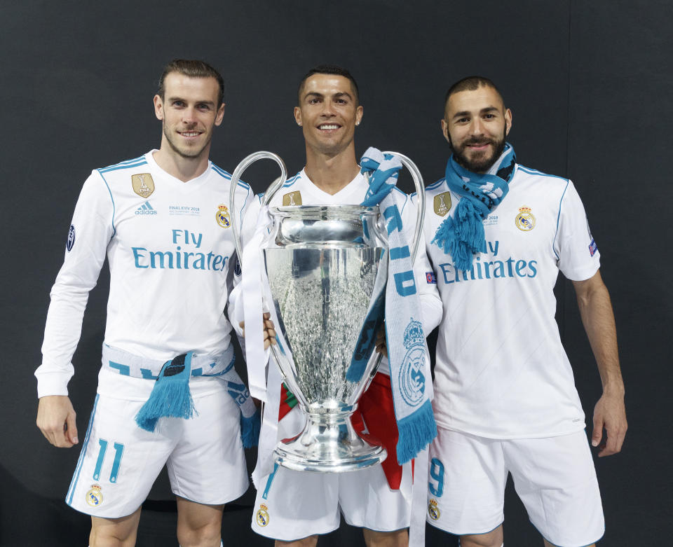 MADRID, SPAIN - MAY 27: Cristiano Ronaldo (2ndL) of Real Madrid CF holds the trophy as he poses for a picture with his teammates Karim Benzema (R) and Gareth Bale (L) during the celebration with their fans at Santiago Bernabeu Stadium the day after winning the UEFA Champions League Final match against Liverpool on May 27, 2018 in Madrid, Spain. Real Madrid CF is the only European football team with 13 European Cups (Photo by Helios de la Rubia/Real Madrid via Getty Images)