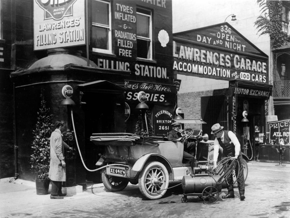 A man fills up his automobile at a fueling station in 1924