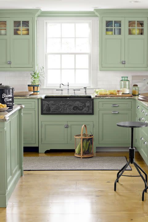 a kitchen with green upper and lower cabinets and a black slate chalkboard like sink