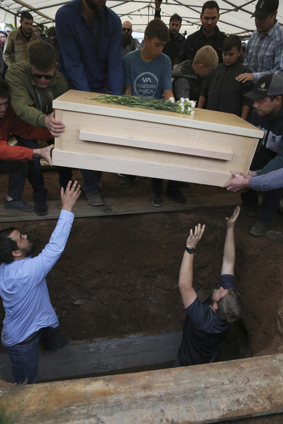 The coffin that contains the remains of 12-year-old Howard Jacob Miller Jr. is lowered into a grave at the cemetery in Colonia Le Baron, Mexico, Friday, Nov. 8, 2019, during a burial service for Rhonita Miller and four of her young children, who were murdered by drug cartel gunmen. The bodies of Miller and four of her children were taken in a convoy of pickup trucks and SUVS, on the same dirt-and-rock mountainous road where they were killed Monday, for burial in the community of Colonia Le Baron in Chihuahua state. (AP Photo/Marco Ugarte)