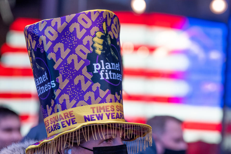 NEW YORK, NEW YORK - DECEMBER 29: A woman wearing a 2022 Planet Fitness hat watches as confetti is released from the Hard Rock Cafe marquee during a ‘confetti test’ ahead of New Year’s Eve in Times Square on December 29, 2021 in New York City. On New Year’s Eve 3000 pounds of confetti will be released. Mayor Bill de Blasio announced that New Year's Eve in Times Square will be limited to 15,000 socially distanced visitors that will be required to be fully vaccinated due to a rise in COVID-19 cases. (Photo by Alexi Rosenfeld/Getty Images)