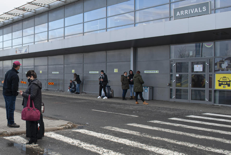 People stand outside the arrivals area of the Sibiu International airport in central Romania, Tuesday, Dec. 28, 2021. As the fast-spreading coronavirus variant omicron rages through Western Europe, officials and experts in low-vaccinated Eastern Europe view it as a forewarning for what much of the region anticipates to be an imminent, post-holiday virus surge.(AP Photo/Stephen McGrath)