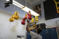 Theon Davis, 21, grabs gloves as he trains for his 176-pound Chicago Golden Gloves tournament boxing match at Garfield Park Boxing Wednesday, March 29, 2023, in Chicago. (AP Photo/Erin Hooley)