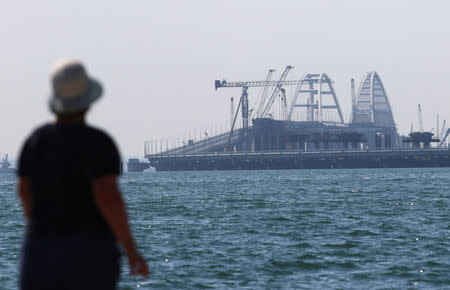 A woman looks at a bridge, which was constructed to connect the Russian mainland with the Crimean Peninsula across the Kerch Strait, on an embankment in the city of Kerch, Crimea May 16, 2018. REUTERS/Pavel Rebrov