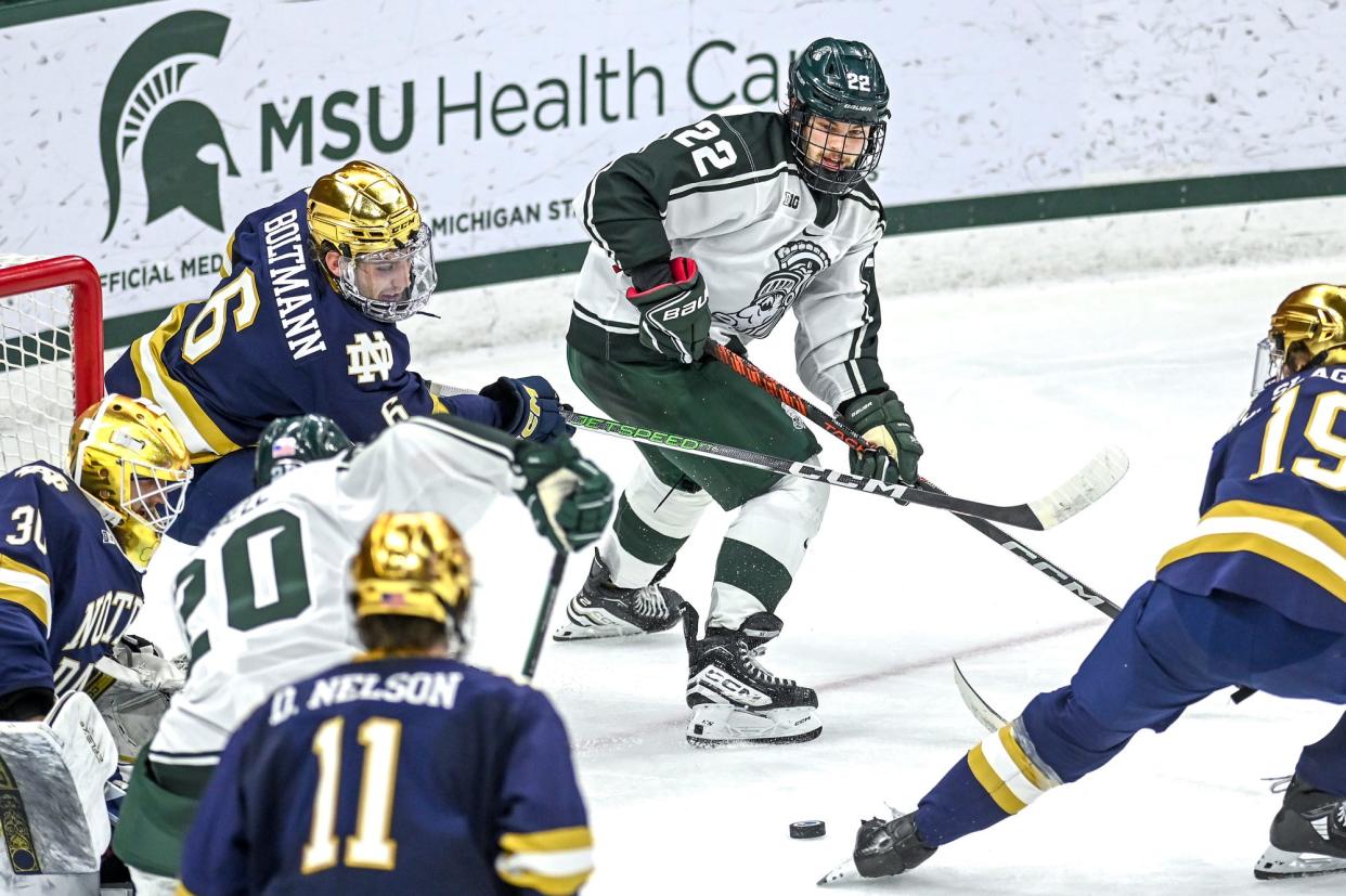 Michigan State's Isaac Howard, center, passes the puck near teammate Daniel Russell during the second period in the game against Notre Dame on Friday, Dec. 8, 2023, at Munn Arena in East Lansing.