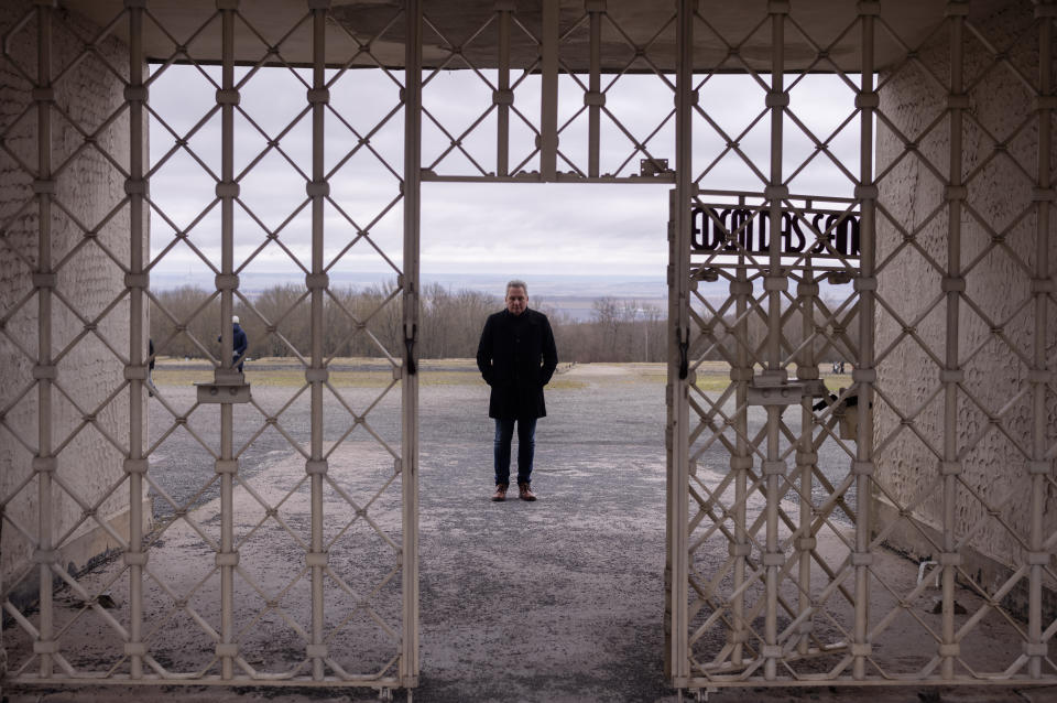 The head of the Buchenwald Memorial, Jens-Christian Wagner, poses for a photo behind the main gate of the former Nazi concentration camp in Weimar, Germany, Wednesday, Jan. 31, 2024. Attacks on the site have stepped up massively in recent months: Wagner says this is because of the "revisionist, antisemitic and racist slogans" promoted by the far-right Alternative for Germany, or AfD party. (AP Photo/Markus Schreiber)