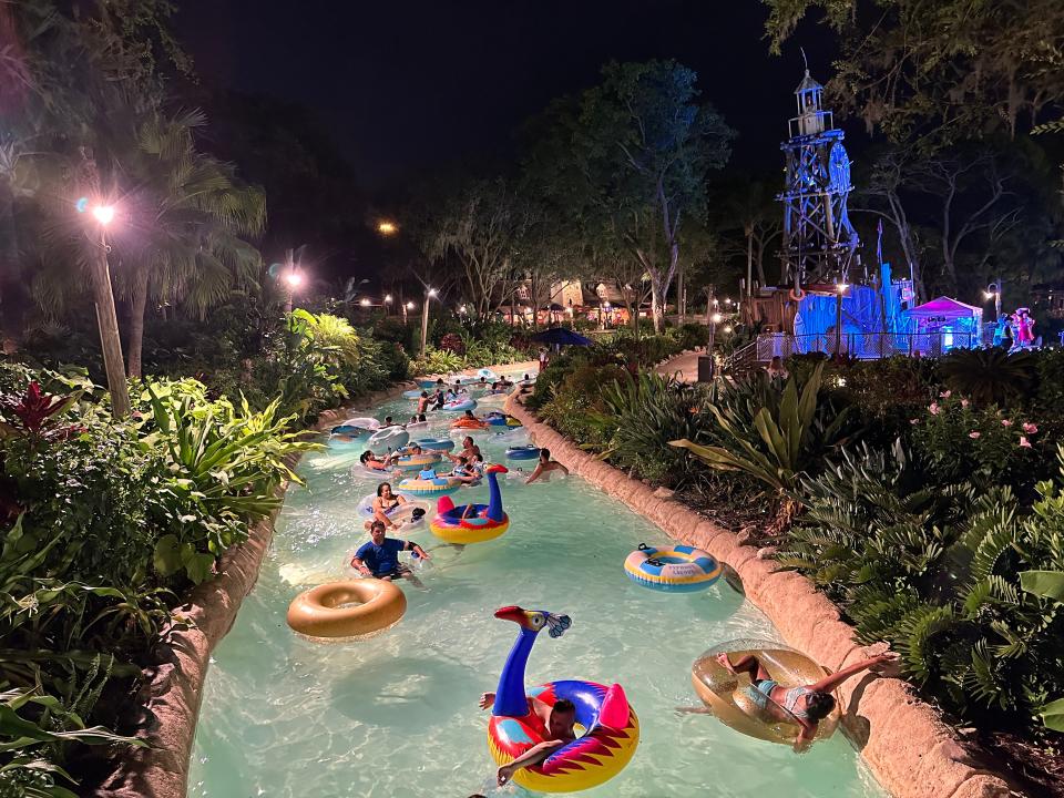 lazy river at night, people sitting on tubes as they float through greenery in the dark