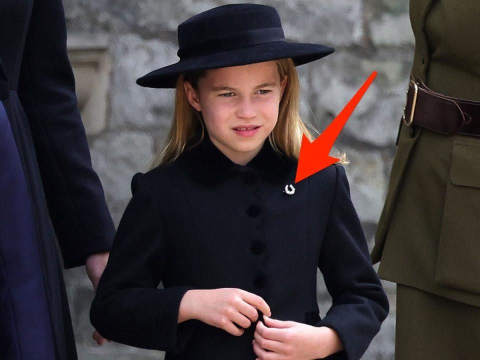 arrow pointing to charlotte's horseshoe broach at the queen's funeral
