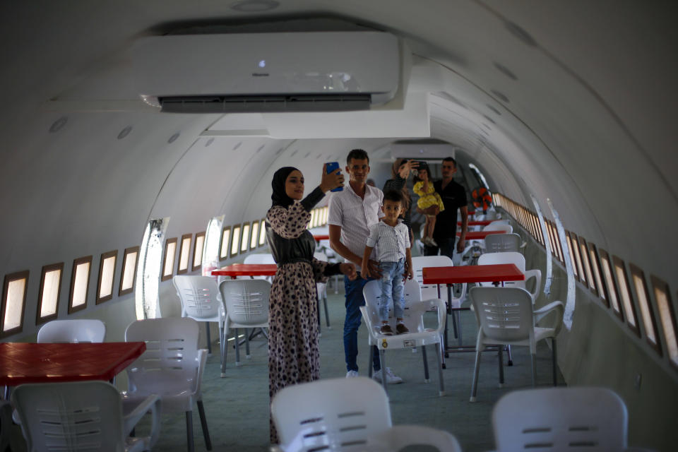 Palestinians visit the interior of a Boeing 707 after it was converted to a cafe restaurant, in Wadi Al-Badhan, near the West Bank city of Nablus, Wednesday, Aug. 11, 2021. The Palestinian territory has no civilian airport and those who can afford a plane ticket must catch their flights in neighboring Jordan. After a quarter century of effort, twins brothers, Khamis al-Sairafi and Ata, opened the “Palestinian-Jordanian Airline Restaurant and Coffee Shop al-Sairafi” on July 21, 2021, offering people an old airplane for customers to board. (AP Photo/Majdi Mohammed)